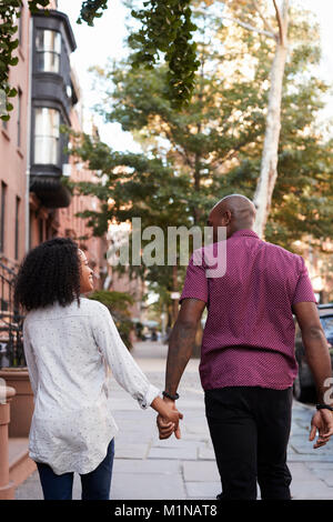 Vue arrière du couple en train de marcher le long de la rue en milieu urbain dans la ville de New York Banque D'Images