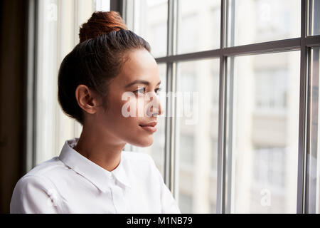 Young businesswoman with hair bun à la fenêtre de Banque D'Images