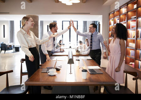 Quatre collègues fêter la réussite dans un open plan office Banque D'Images