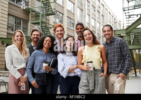 Friendly collègues rient à l'appareil photo à l'extérieur de leur lieu de travail Banque D'Images