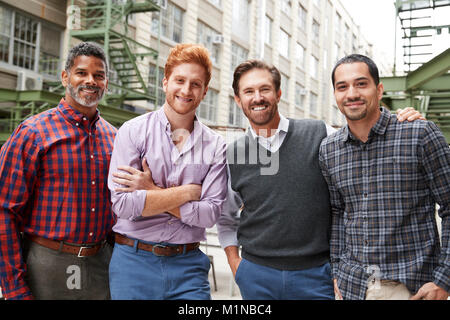 Quatre collègues masculins à l'extérieur de l'appareil photo en souriant Banque D'Images