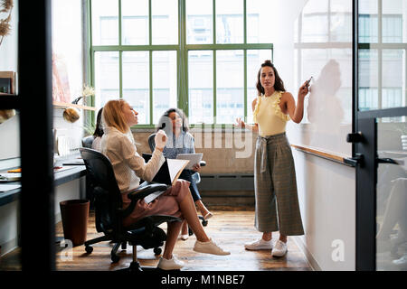 Femme à la recherche de tableau blanc lors d'une réunion avec l'équipe féminine Banque D'Images