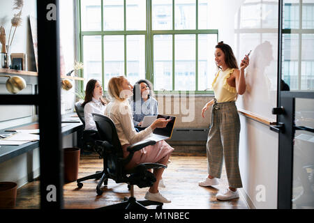 Woman pointing at whiteboard lors d'une réunion avec l'équipe féminine Banque D'Images