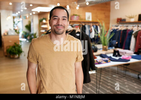 Smiling young Hispanic man standing dans un magasin de vêtements Banque D'Images