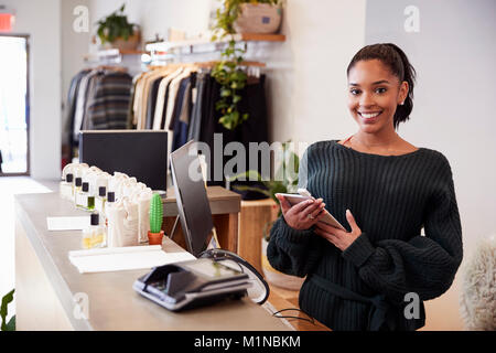 Assistante smiling du comptoir de magasin de vêtements Banque D'Images