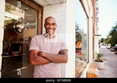 Jeune homme noir souriant pour ses vêtements à l'extérieur de l'appareil photo shop Banque D'Images