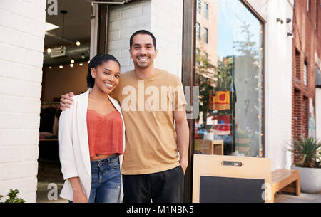Young Hispanic couple smiling to camera en dehors de leur shop Banque D'Images
