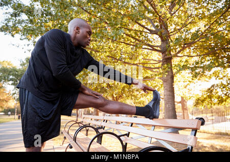 Jeune homme noir qui s'étend une jambe dans le Brooklyn Park Banque D'Images