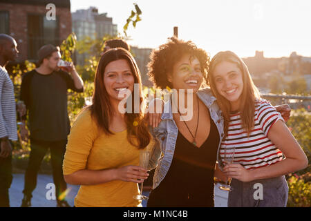 Femme amis lors d'une soirée sur le toit de l'appareil photo en souriant Banque D'Images