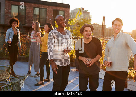 Trois amis de rire et de l'alcool à une soirée sur le toit Banque D'Images