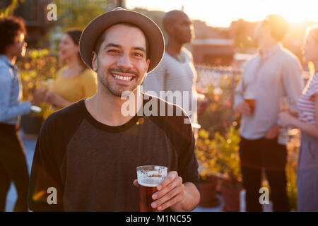 Jeune homme à un toit-party smiling to camera Banque D'Images