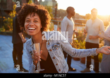 Young woman dancing at a rooftop party smiling to camera Banque D'Images
