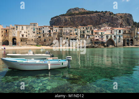 Deux bateaux canot dans les eaux vert émeraude du petit port à la plage de la ville, dans la vieille ville de Cefalu près de Palerme en Sicile, Italie. Banque D'Images