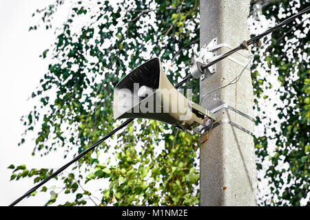 Haut-parleur se bloque sur un mât sur l'arrière-plan de feuilles d'arbres. Banque D'Images