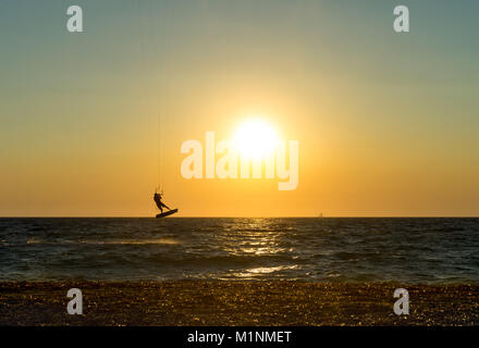 Kite surfer bondissaient hors de l'eau de l'océan au coucher du soleil Banque D'Images