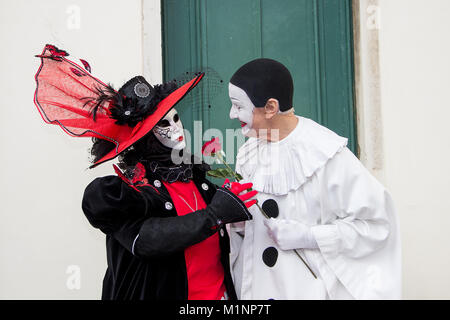 Couple de masques Vénitiens - Pierrot et la femme en rouge et rose sur la place San Zaccaria à Venise, Italie Banque D'Images