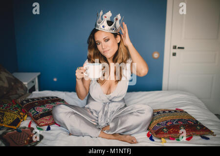 La jeune fille avec la couronne allongée sur le lit dans la chambre, Banque D'Images