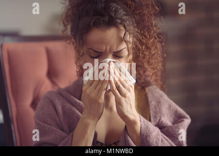 Woman blowing son nez qui coule et les éternuements dans un mouchoir en papier Banque D'Images