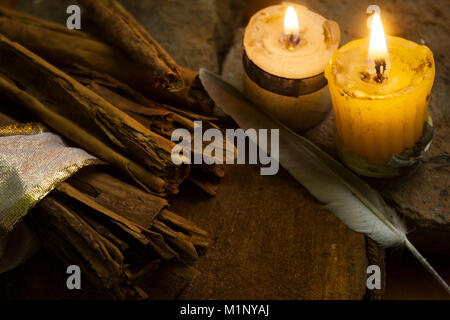 Les bâtons de cannelle sur table en bois avec des bougies et de plumes Banque D'Images