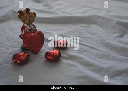 Cute Bear avec des coeurs autour d'elle s'affiche au-dessus d'un drap de lit blanc. Laissant de la place sur la droite pour le texte et les messages. Banque D'Images