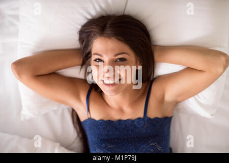 Jeune brunette woman happily couché dans son lit Banque D'Images