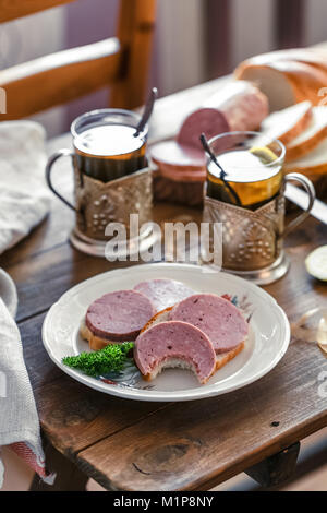 Des sandwichs avec saucisses sur une assiette avec du thé Banque D'Images