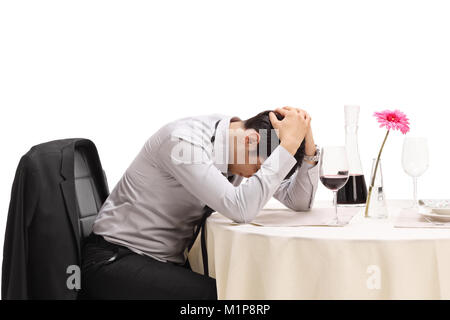 Homme désespéré assis seul à une table de restaurant avec la tête vers le bas, isolé sur fond blanc Banque D'Images