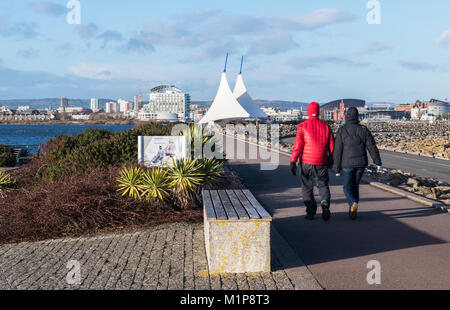 Couple en train de marcher sur la baie de Cardiff Barrage sur une froide journée d'hiver en Janvier Banque D'Images