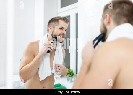 Beau jeune homme barbu, sa barbe de fraisage avec un massicot Banque D'Images