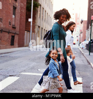 Mère de deux filles avec amis crossing road, Close up Banque D'Images