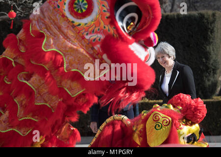 Premier ministre Theresa peut 'Dots' l'œil d'un dragon chinois, un rituel traditionnel de l'éveil d'un dragon, dans l'enceinte de l'ambassade britannique à Beijing aujourd'hui le deuxième jour de trois jours de mission commerciale en Chine. Banque D'Images