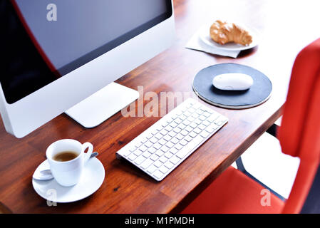 Scène de travail avec petit-déjeuner. Petit-déjeuner de base sur un lieu de travail, un croissant et une tasse à café. Ordinateur, collation et boisson chaude, de scène, pause. Banque D'Images