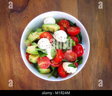 Jardin frais ou salade italienne salade dans un bol blanc. L'avocat, tomate cerise et mozzarella salade avec du basilic frais. close-up shot. Salade gourmande. Banque D'Images