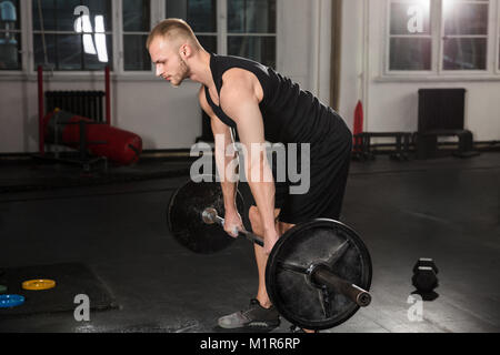 Jeune homme faisant Deadlift Barbell dans la salle de sport Banque D'Images