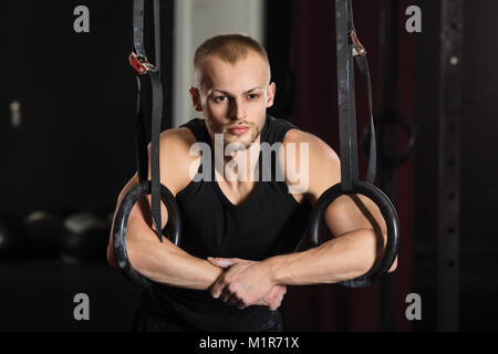 Portrait d'une jeune athlète masculin avec anneaux de gymnastique dans la salle de sport Banque D'Images