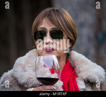 Vieille Femme avec mouchoir rouge boire du vin en verre en verre Banque D'Images