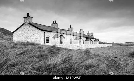 Une photographie en noir et blanc d'une rangée de vieilles maisons de pêcheurs sur la plage Banque D'Images