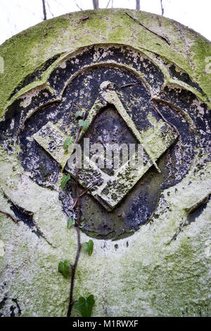 Une pierre tombale maçonnique à Tower Hamlets Cemetery avec la signature du franc-maçon square et gravée à l'emblème de la boussole en décomposition lentement en pierre. Banque D'Images