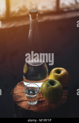 Pomme, ambiance rétro rustique. Bouteille et seul verre à boire de l'alcool de pomme verte et deux fruits. Banque D'Images