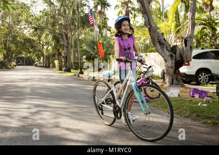 Jeune fille de descendre du vélo sur une rue de banlieue Banque D'Images