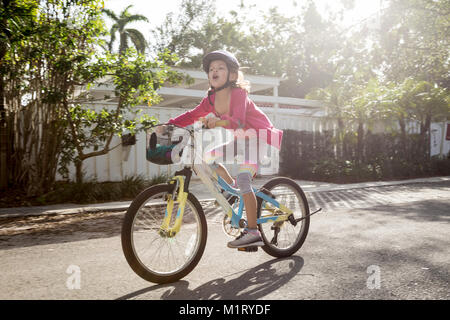 Jeune fille appelant à des amis tout en vélo sur la rue de banlieue Banque D'Images
