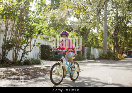 Young Girl riding bicycle sur rue de banlieue Banque D'Images