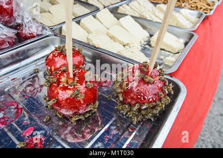 Pommes rouges sucrés au sucre glacé et abeilles sur eux. Banque D'Images