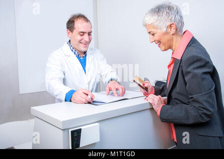 Dame âgée heureux de payer sa facture médicale Banque D'Images