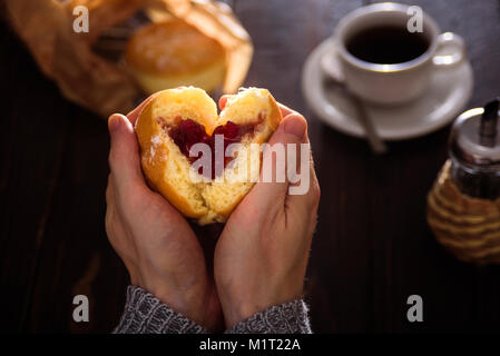 Man hands holding heart-shaped donut avec berry jam Banque D'Images