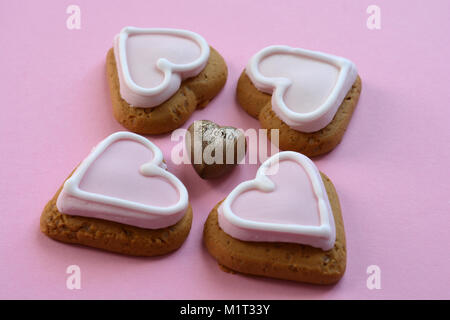 Gingerbread cookies en forme de coeur quatre avec glaçage rose, sur un fond rose Banque D'Images