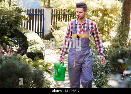 Homme avec arrosoir au jardin Banque D'Images