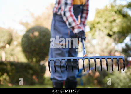 Homme de flou artistique le ratissage des feuilles au jardin Banque D'Images