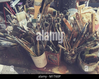 L'abondance des pinceaux dans des pots et des boîtes en studio de l'artiste Banque D'Images