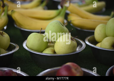 La pomme verte fraîche dans un bol entouré d'autres bols de fruits et bananes jaunes à un fruit market stall Banque D'Images